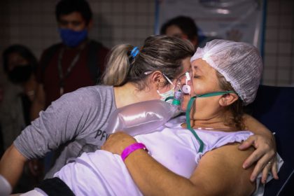 20 January 2021, Brazil, Manaus: A woman wearing a mask hugs a Covid 19 patient who is to be flown out from Joao Lucio Hospital in Manaus to a hospital in Maceio, Alagoas state. There are almost no free public hospital and intensive care beds left in the Amazon capital Manaus. The city's capacity to produce oxygen covers less than a third of current demand, according to the organization Doctors Without Borders. (to dpa "Manaus' second collapse: Amazon metropolis runs out of oxygen" from 22.01.2021) Photo: Lucas Silva/dpa (Photo by Lucas Silva/picture alliance via Getty Images)