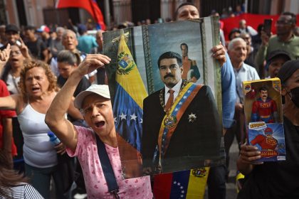A woman holds a portrait of Venezuelan President Nicolas Maduro during a gathering in Caracas on January 3, 2026, after US forces captured him. President Donald Trump said Saturday that US forces had captured Venezuela's leader Nicolas Maduro after bombing the capital Caracas and other cities in a dramatic climax to a months-long standoff between Trump and his Venezuelan arch-foe. (Photo by Federico PARRA / AFP)